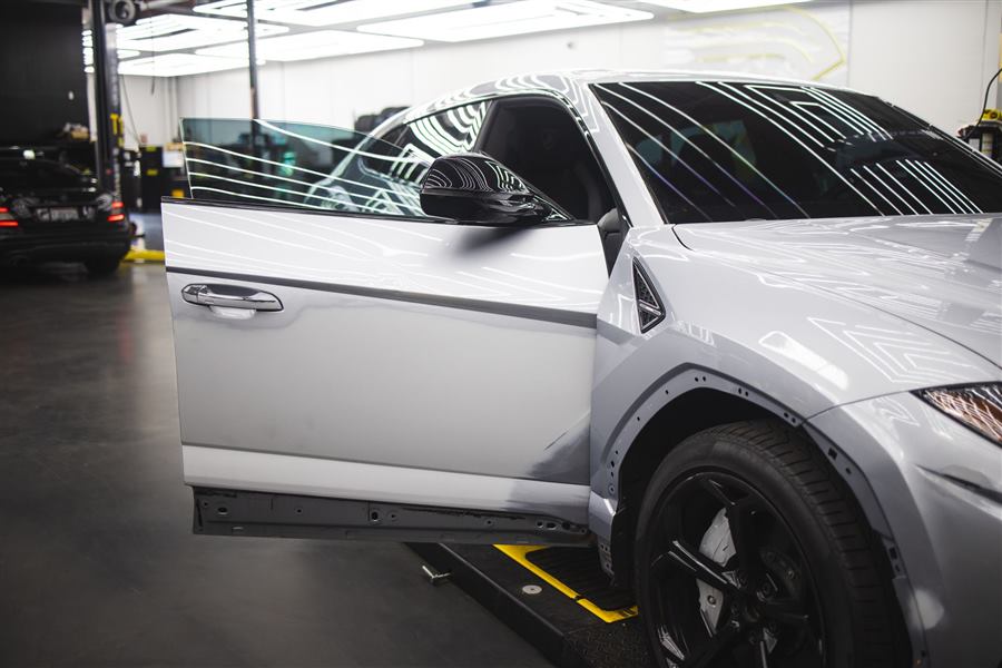 A gray SUV with its door open on a lift in a dark workshop