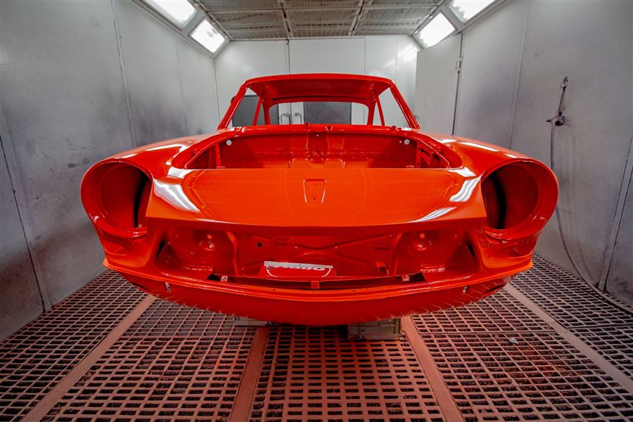 A freshly painted red car body in a spray booth