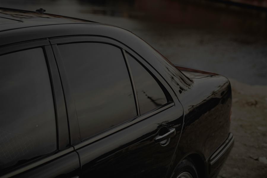 The tinted side windows of a black sedan